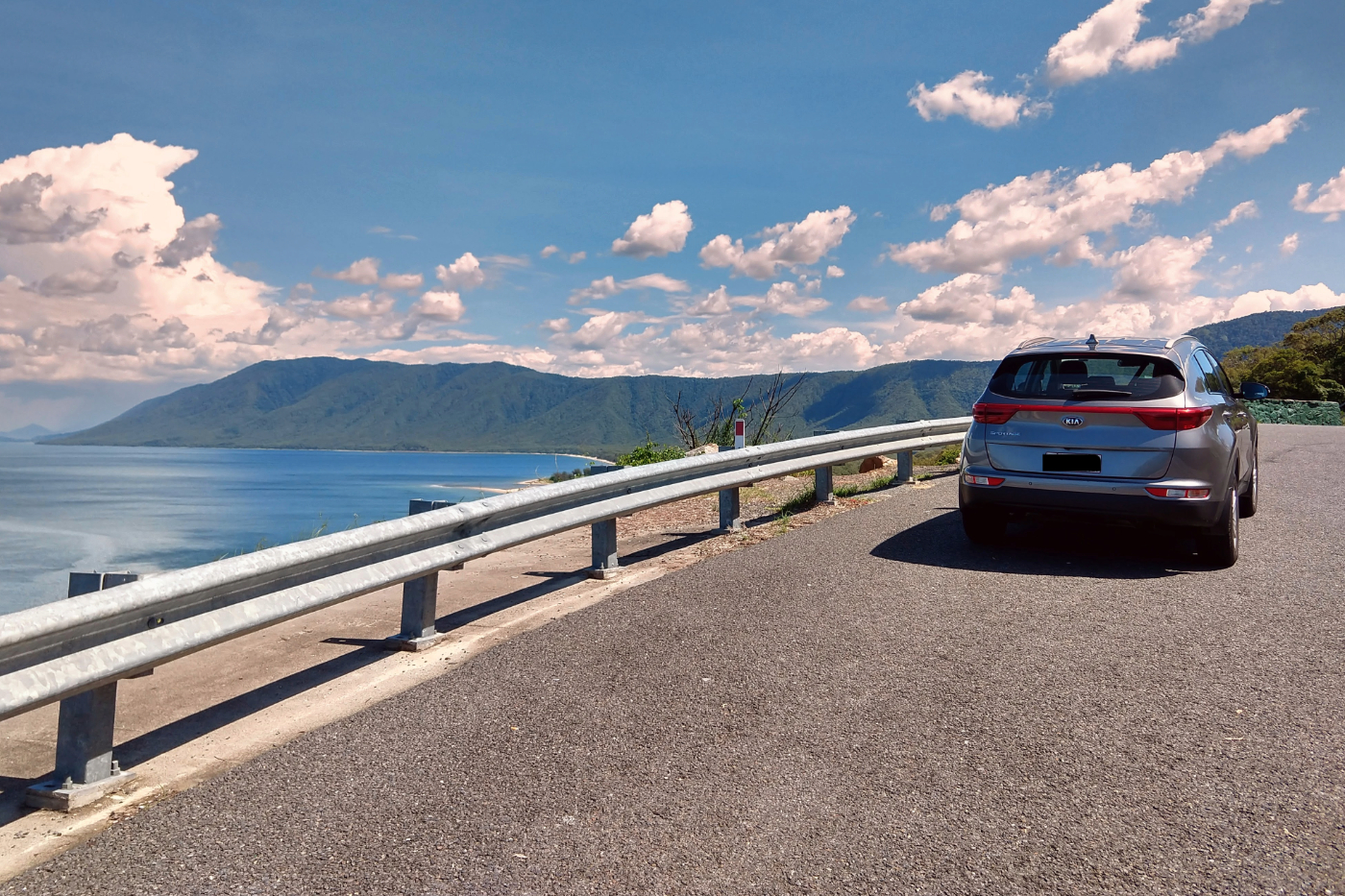 port douglas to cairns scenic drive, blue car on the road next to the coral sea