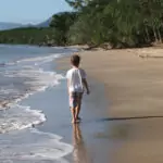 Things To Do in Port Douglas With Kids A child walking on Port Douglas Beach.